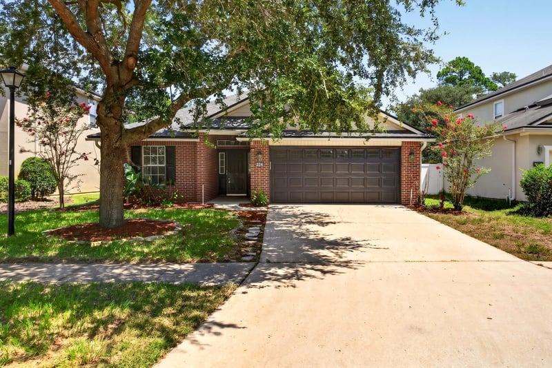 Front exterior with three-car garage and large shade tree at 224 Pine Arbor Cir, St. Augustine, FL 32084