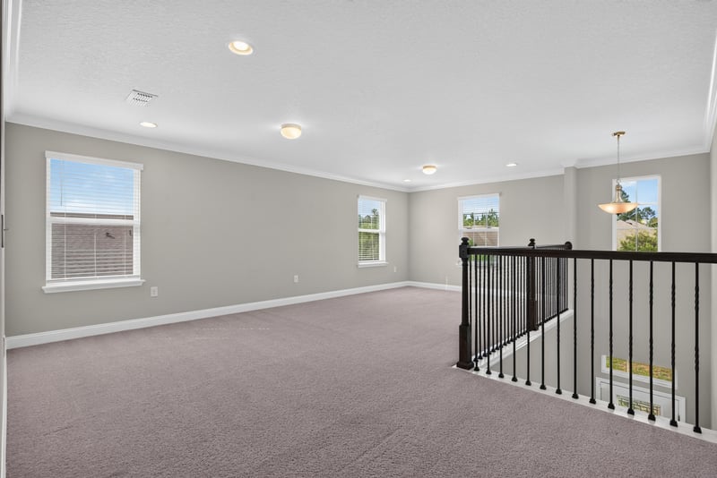 Carpeted living area with stair railing above at 2580 Cold Stream Ln, Green Cove Springs, FL 32043