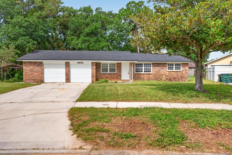 Front exterior of brick ranch home with driveway and mature trees at 9954 Larkdale Ct, Jacksonville, FL 32257