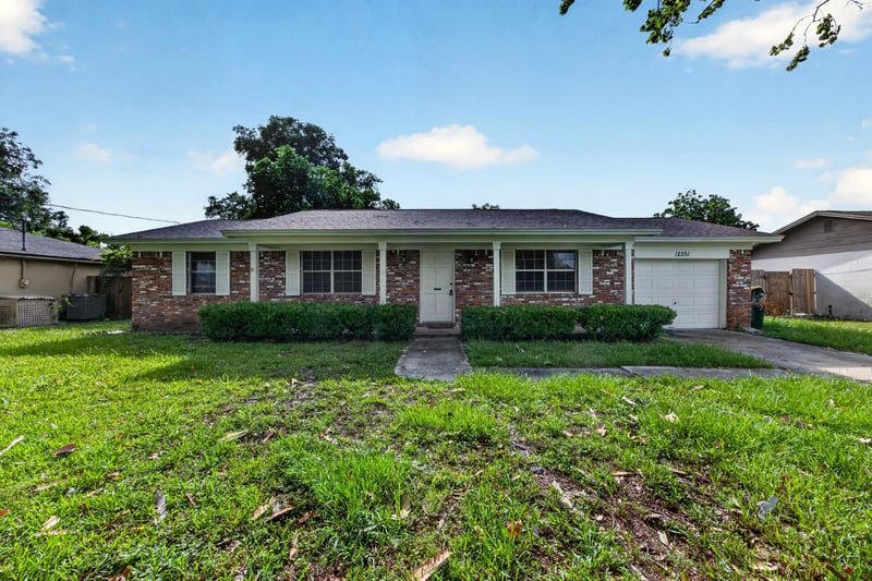 Brick ranch front exterior with attached garage and lawn at 12351 Condor Dr