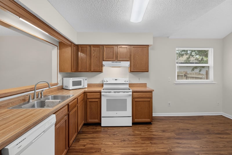 Kitchen sink area with white range and oak cabinets at 4427 Millstone Ct, Jacksonville, FL