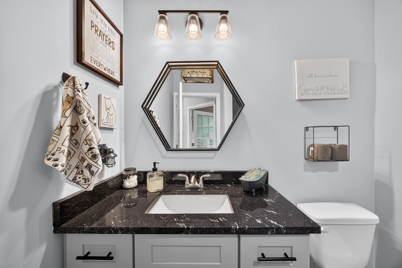 Bathroom vanity with hexagon mirror and black countertop at 2817 Camel Cir, Middleburg, FL