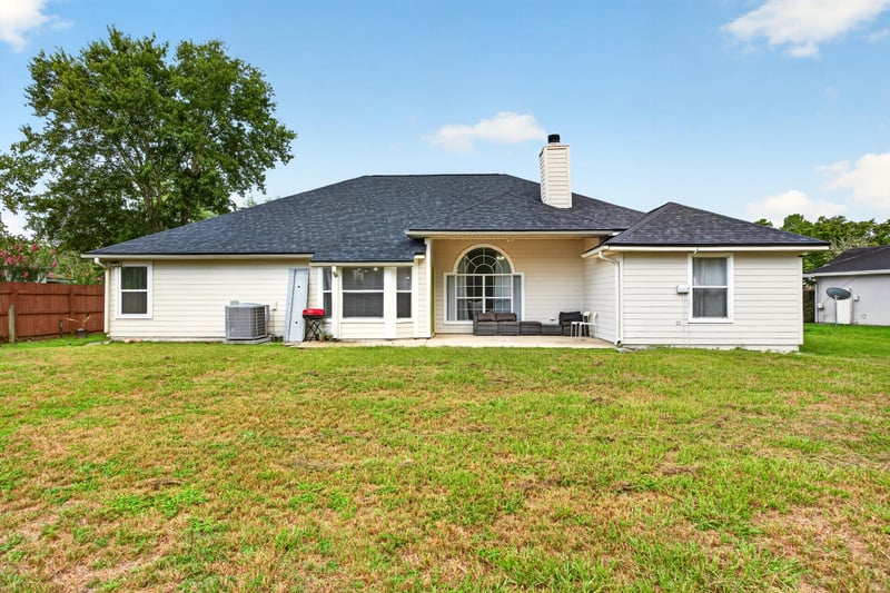 Backyard with covered patio and open lawn at 8921 Needlepoint Pl, Jacksonville, FL 32244