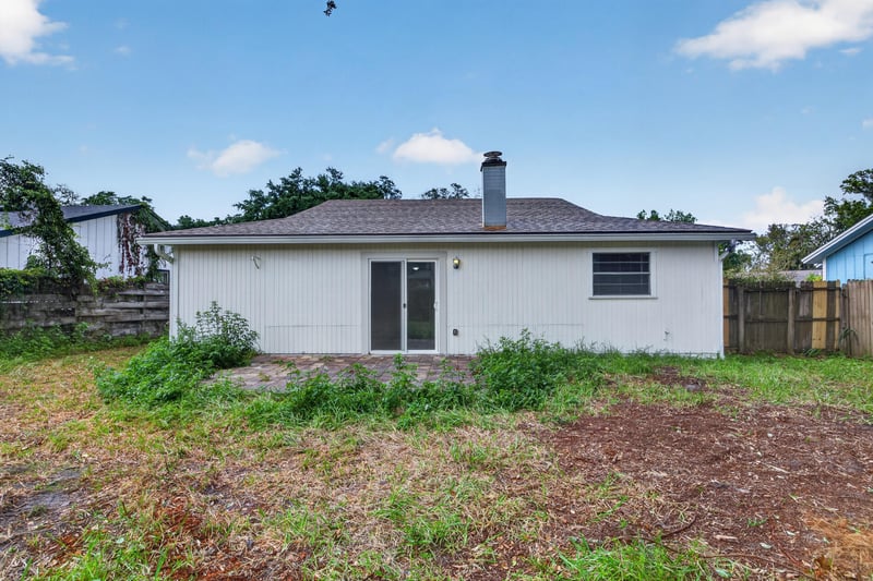 Rear exterior with sliding glass door and chimney at 1040 Willow Cove Ct E, Jacksonville, FL 32233