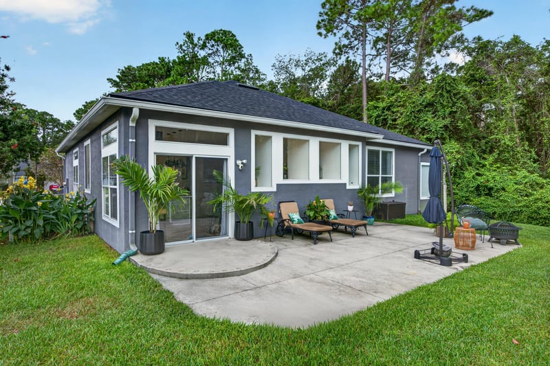 Back exterior with covered patio and lawn at 1820 Burgess Hill Dr E, Jacksonville, FL