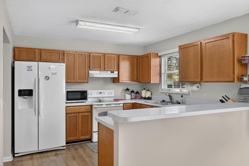 Kitchen with wood cabinets and white appliances at 8680 Bandera Cir S, Jacksonville, FL 32244