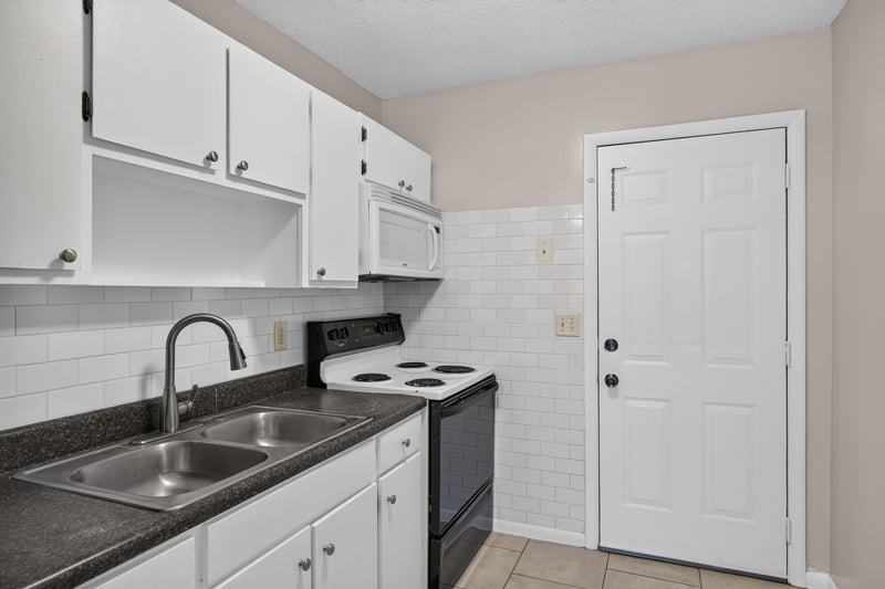 Kitchen sink and stove with white cabinetry at 8067 Parental Cir, Jacksonville, FL 32216