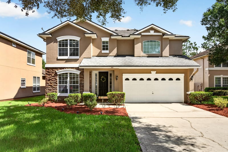 Front exterior with three-car garage and mature trees at 3660 Middlebrook Dr, Orange Park, FL 32065