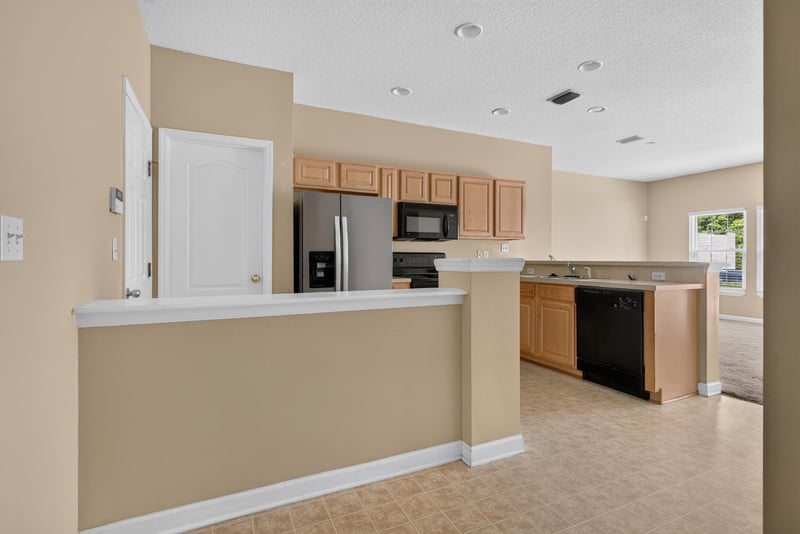 Kitchen pass-through counter with black appliances at 12359 Mangrove Forest Ct, Jacksonville, FL 32218