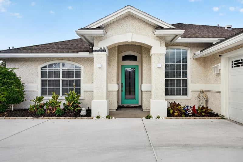 Front entry with arched doorway and teal door at 12825 Kelsey Island Dr, Jacksonville, FL 32224