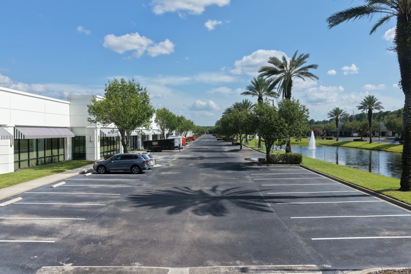 Parking lot with palm trees and pond beyond at 10550 Deerwood Park Blvd, Jacksonville, FL 32256