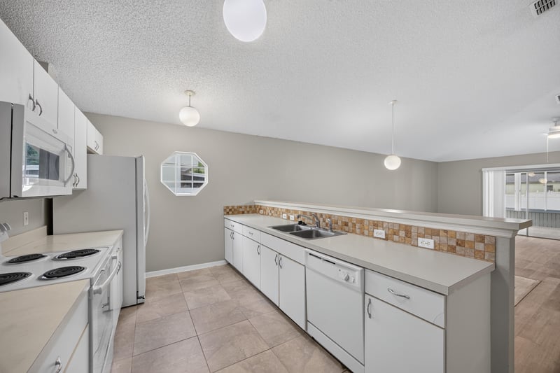Kitchen with white cabinets and tile backsplash at 1845 Saga Ct, Middleburg, FL