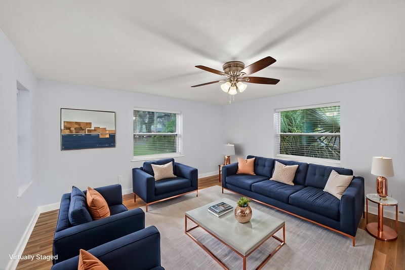 Staged living room with blue sofas and ceiling fan at 1619 Hammond Blvd, Jacksonville, FL