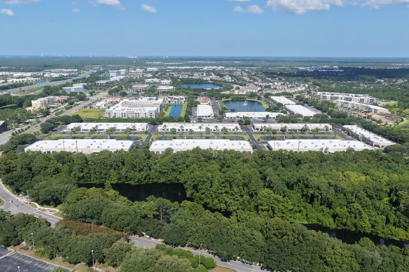 Wide aerial view of the office park with pond and tree line at 10550 Deerwood Park Blvd, Jacksonville, FL 32256