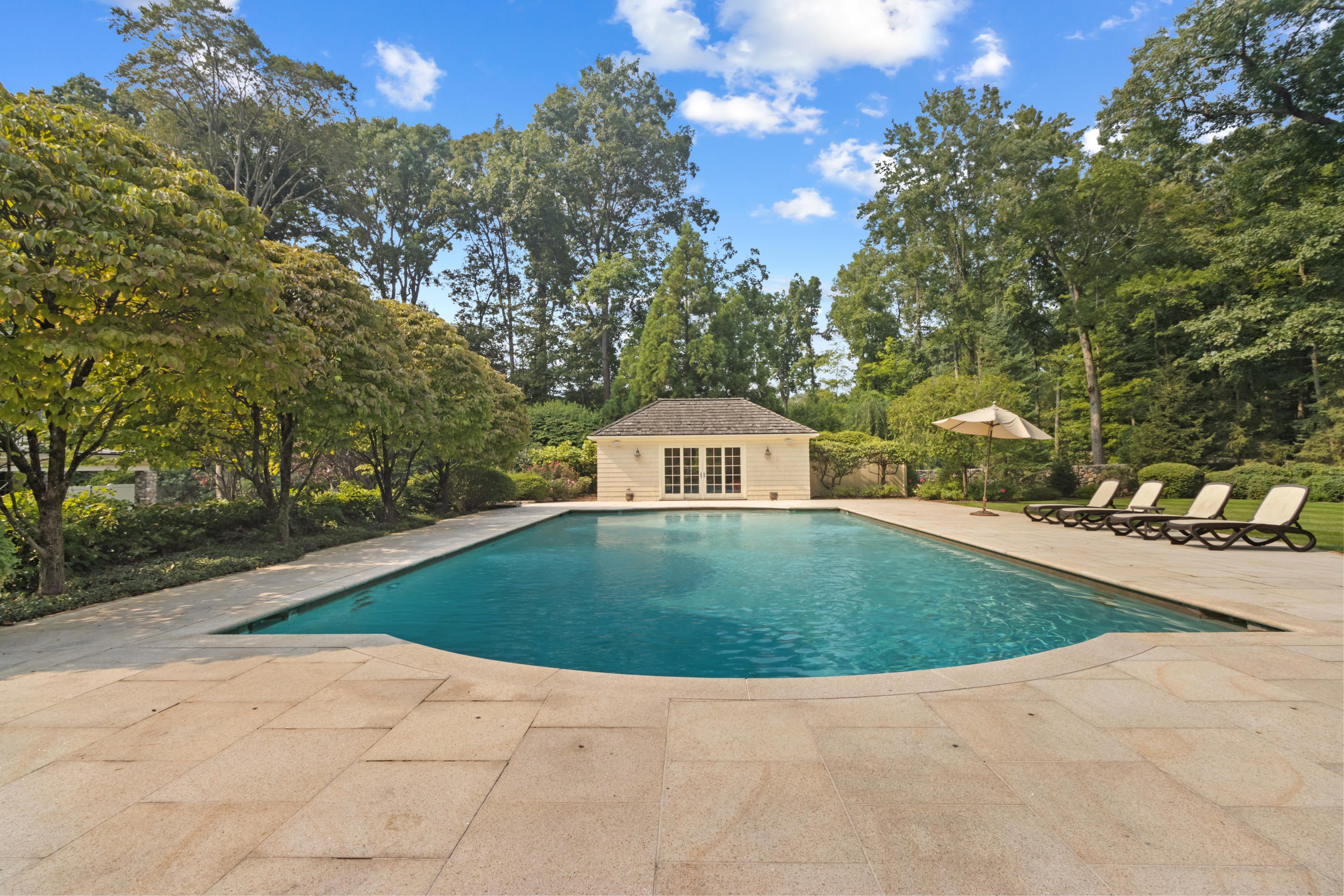 Swimming pool and pool house surrounded by mature trees