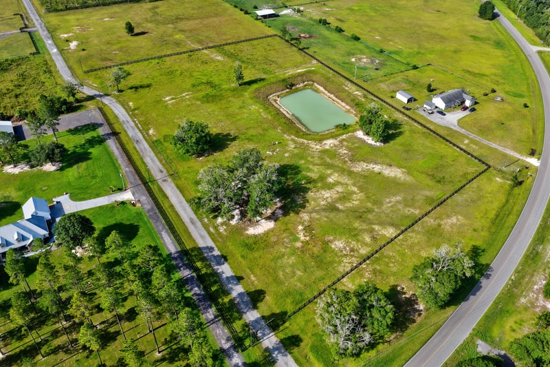 Aerial view of a pond and curved road serving nearby rural properties at 7500 Lucky Seven Rnch Rd, Macclenny, FL