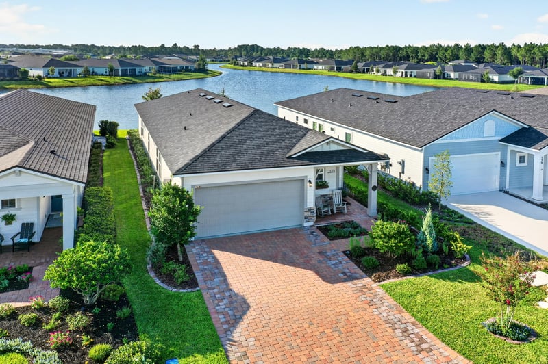 Day-to-dusk aerial of the home and backyard pond at 129 Amberwood Dr, St. Augustine, FL