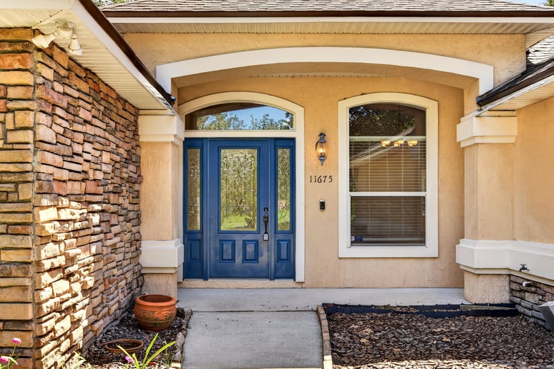 Front entry with stone trim and double blue doors at 11675 Magnolia Estates Rd, Jacksonville, FL 32223