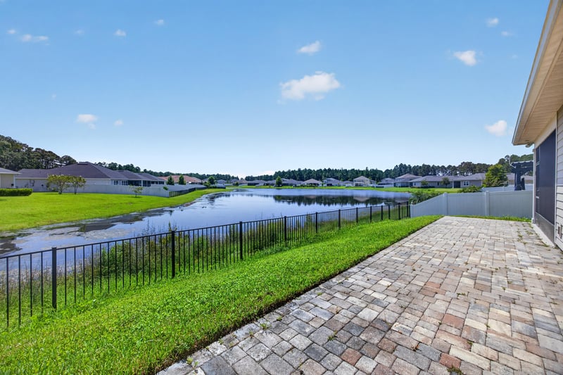 Paver patio and fenced backyard with pond at 855 Flach Dr, St. Johns, FL