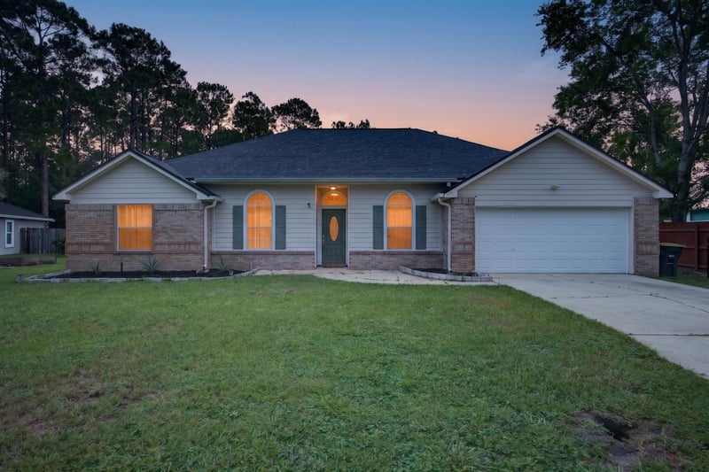 Front exterior at day-to-dusk with porch lights on at 8921 Needlepoint Pl, Jacksonville, FL 32244