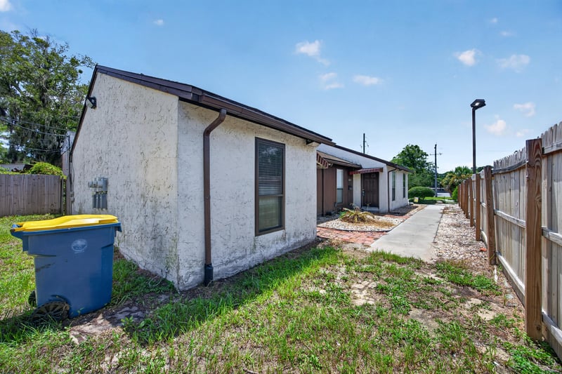 Side exterior with paved walkway and fence at 2719 Trollie Ln