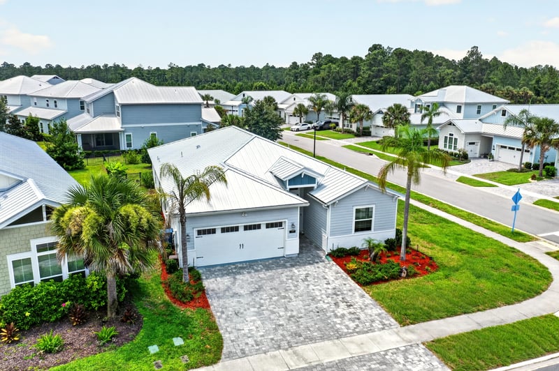 Front elevation from above with metal roof, palms and landscaped beds at 91 Tilloo Ct, St. Johns, FL