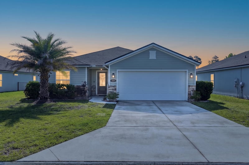 Front exterior at day-to-dusk with illuminated windows at 589 Seville Pkwy, St. Augustine, FL
