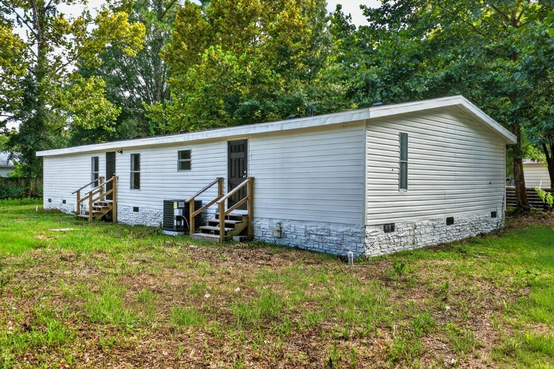 Rear exterior with deck and wooded backdrop at 55520 Jewel-Thomas Rd, Callahan, FL 32011
