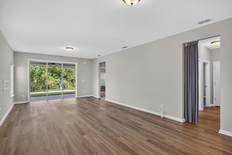 Living room with wood floor and curtained sliding door at 75875 Saffron Ln, Yulee, FL 32097