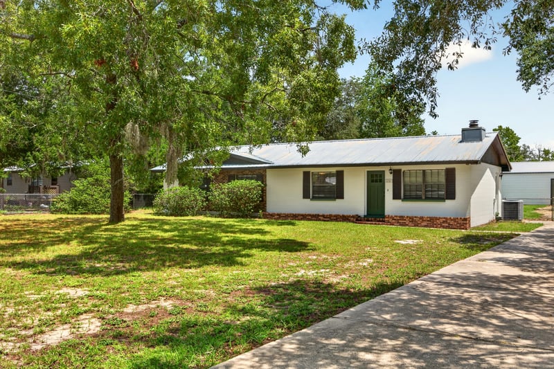 Front exterior with chimney and shaded oak trees at 6757 Deer Springs Rd, Keystone Heights, FL 32656