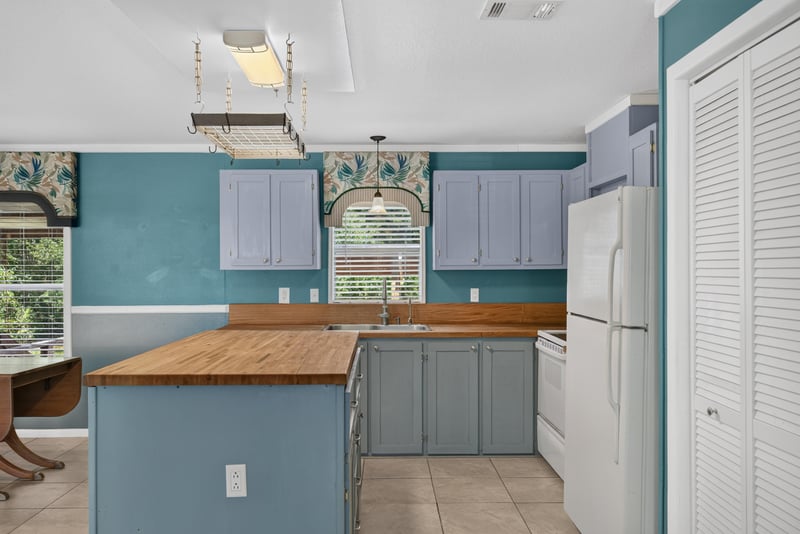 Kitchen with teal walls, gray cabinets and white refrigerator at 2549 Snapdragon Ave, Middleburg, FL 32068