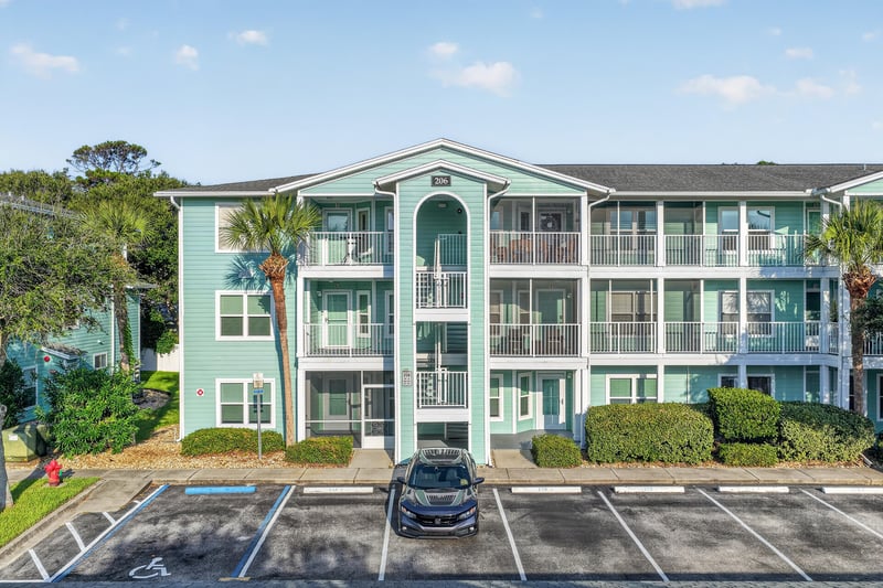 Front exterior of the teal condo building with parking area at 206 16th St, St. Augustine, FL 32080
