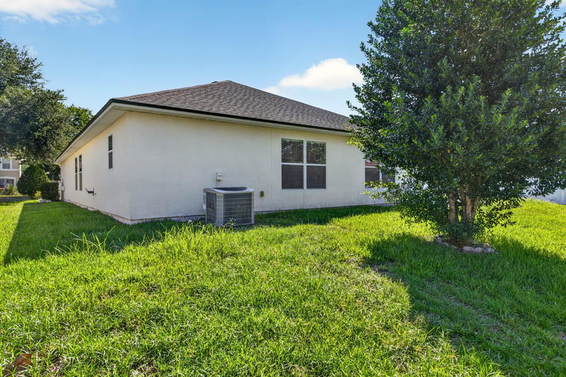 Backyard with AC unit and open lawn at 2282 Justin Lake Dr, Jacksonville, FL