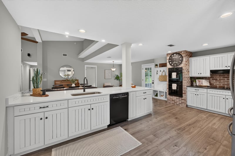 Kitchen with white cabinets open to living room at 1161 Whispering Pines Rd, Jacksonville, FL 32259