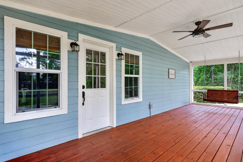 Exterior close-up of blue siding, white windows, and wood deck at 4890 McAllister Rd, Middleburg, FL 32068