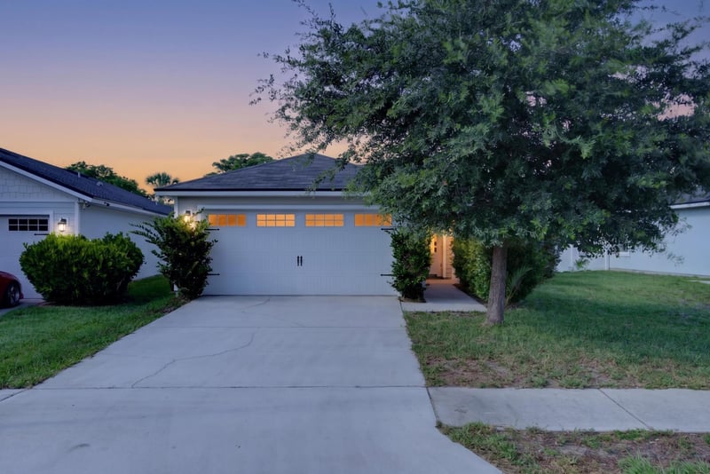 Front exterior at day-to-dusk with porch light and tree at 7253 Townsend Village Ct, Jacksonville, FL