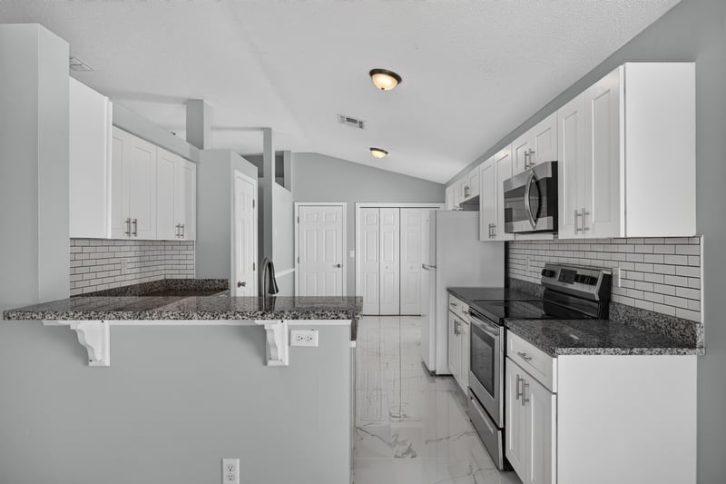 Kitchen with white cabinets, granite counters, and bar seating at 490 Hillside Dr, Orange Park, FL 32073