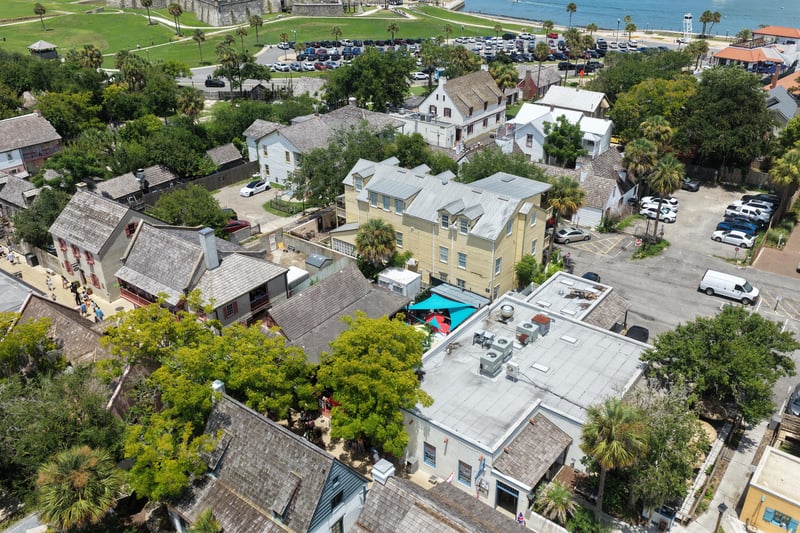 Aerial view of the yellow building complex and adjoining parking lot at 29 Cuna St, St. Augustine, FL 32084