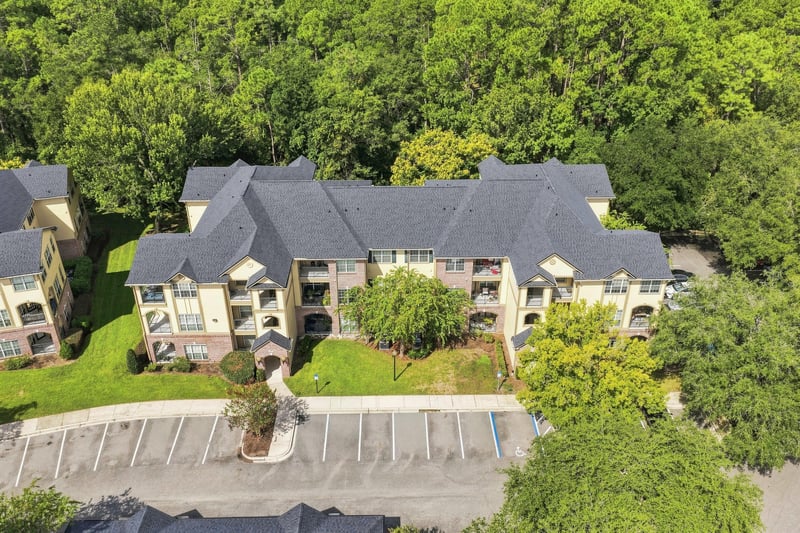 Aerial view of the condo building surrounded by trees at 7800 Point Meadows Dr, Jacksonville, FL 32256