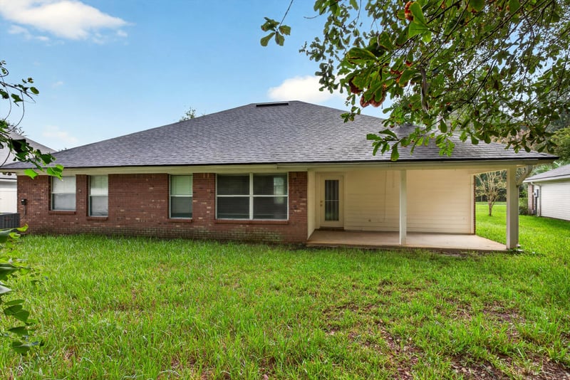 Rear exterior with covered patio and brick facade at 11669 Collins Creek Dr, Jacksonville, FL 32258