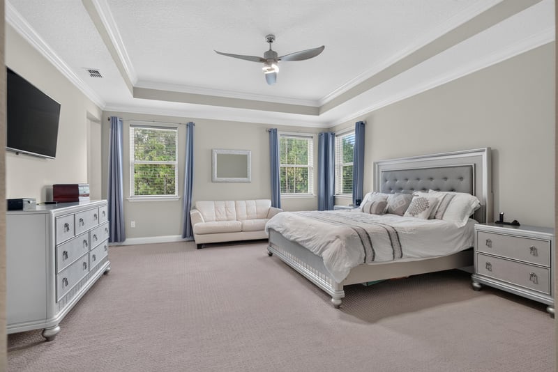Primary bedroom with tray ceiling and TV at 22 Azura Point