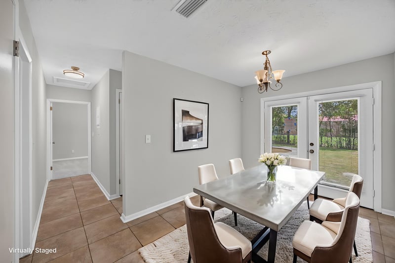 Virtually staged dining area with table, chairs and french doors to yard at 7453 Jade Dr N, Jacksonville, FL 32210