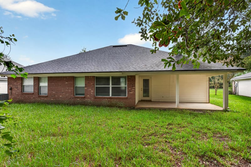Rear exterior with covered patio and brick facade at 11669 Collins Creek Dr, Jacksonville, FL 32258