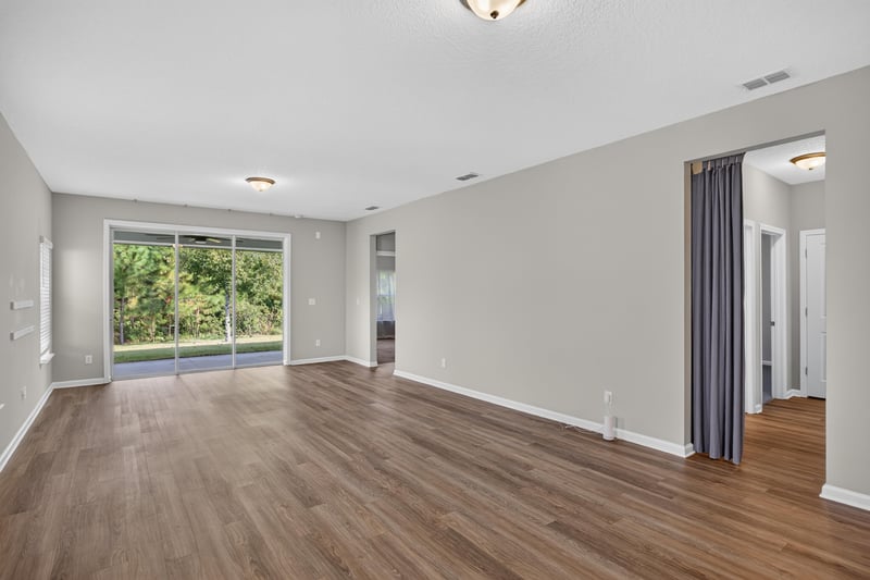 Living area with wood floor and curtained window at 75875 Saffron Ln, Yulee, FL 32097