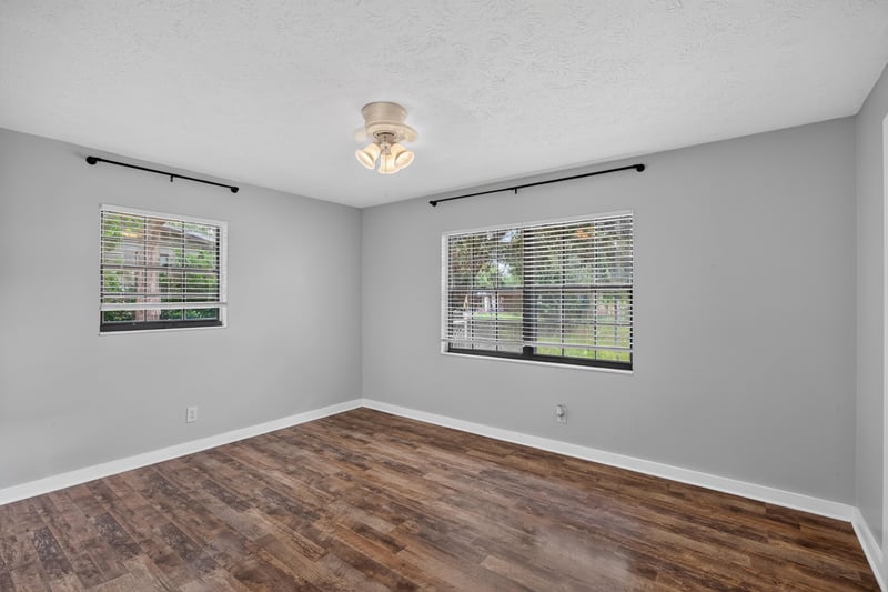 Bedroom with wood-look flooring and two windows at 6757 Deer Springs Rd, Keystone Heights, FL 32656