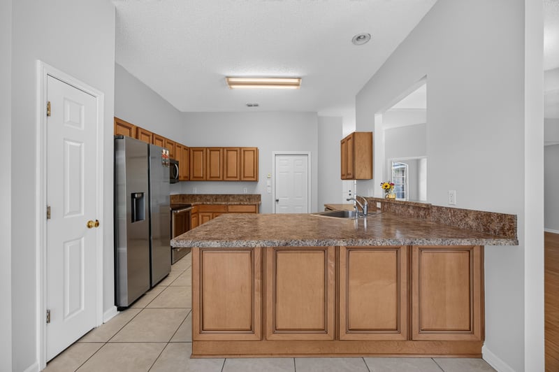 Kitchen island with granite counter and wood cabinets at 456 Bay Point Way N, Jacksonville, FL 32259