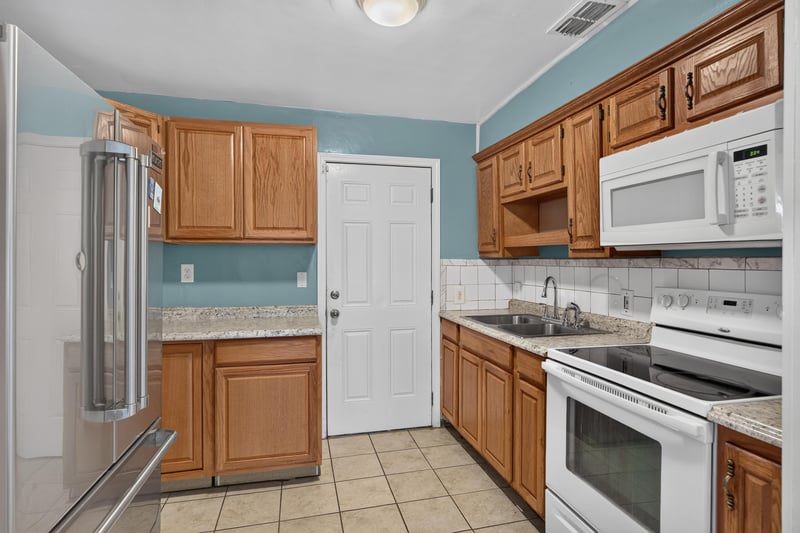 Kitchen with wood cabinets, white appliances and tile floor at 2841 Ernest St, Jacksonville, FL 32205