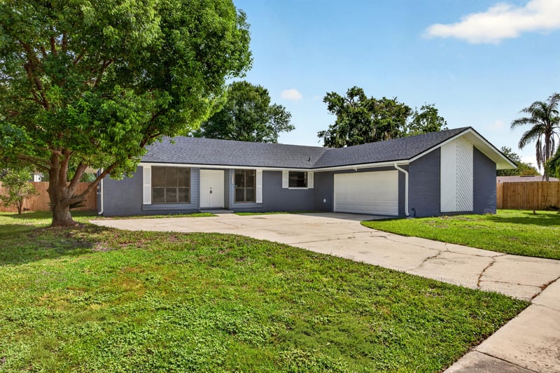 Side angle of front exterior with mature trees and lawn at 4117 Wilcrest Ct, Jacksonville, FL 32277