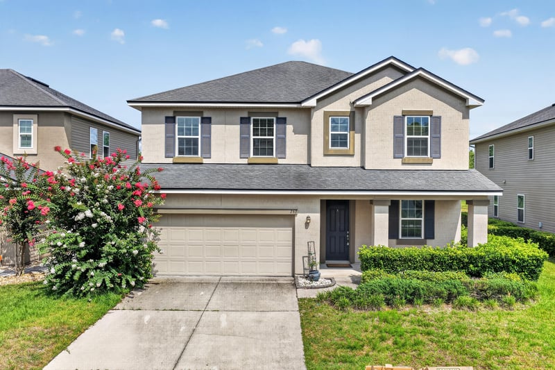 Front exterior of two-story stucco home with two-car garage at 263 Gilmore Ln, Orange Park, FL 32065