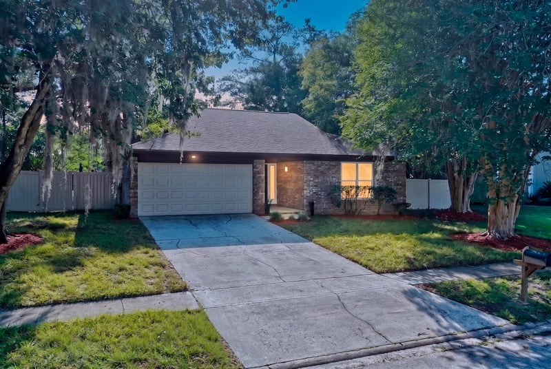 Brick ranch front exterior with two-car garage and mature trees at 8453 Boysenberry Ln W, Jacksonville, FL